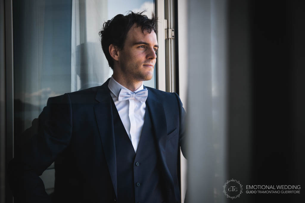 groom looking out of the window in a natural pose taken by a wedding photographer in Napoli