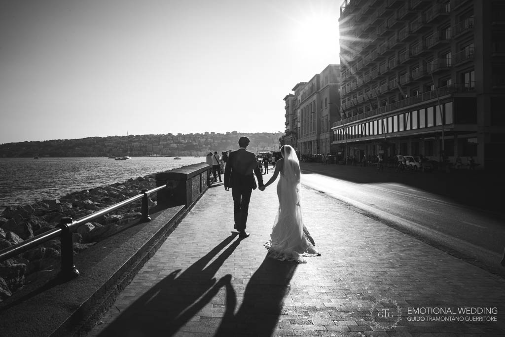 sposi passeggiano sul lungomare di Napoli nel giorno del loro matrimonio