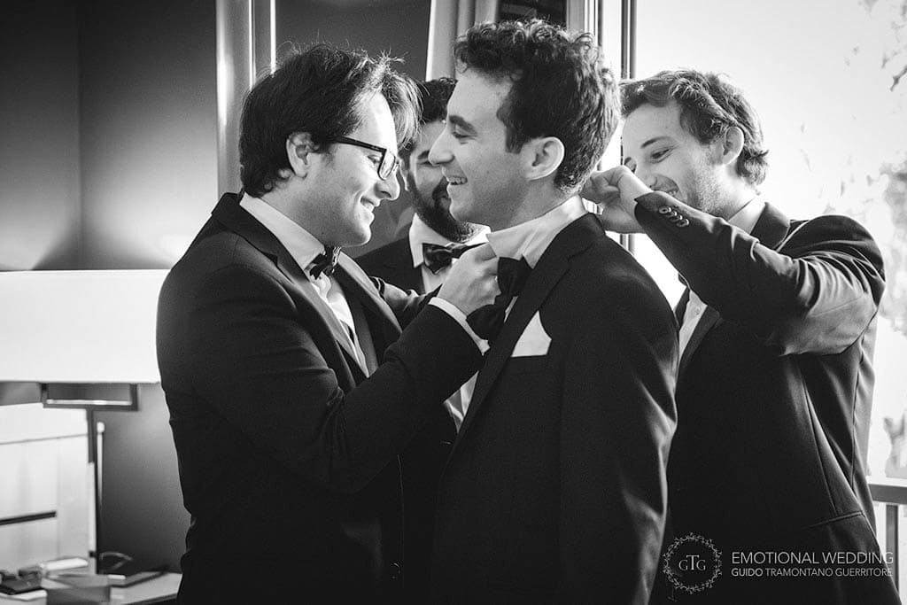 groom gets help getting ready by best men at a wedding in puglia