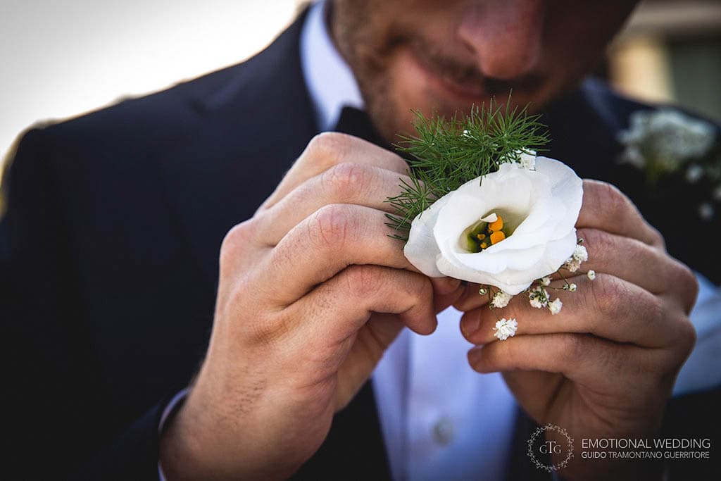 closeup of the groom holding a boutonnière in his hands at a wedding in apulia