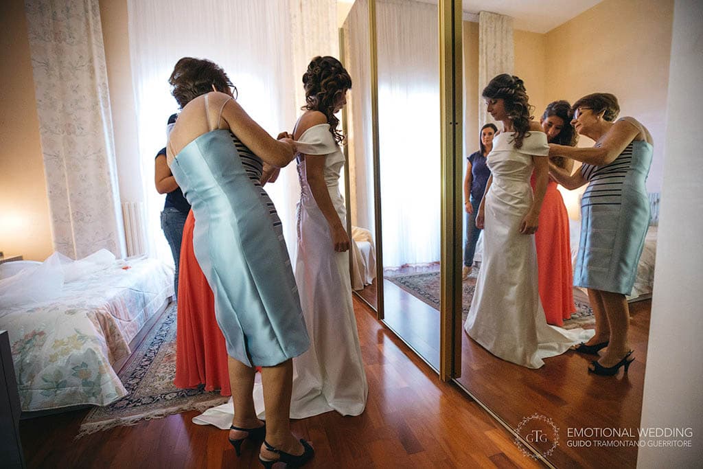mother of the bride and bridesmaid help the bride getting ready at a wedding in apulia