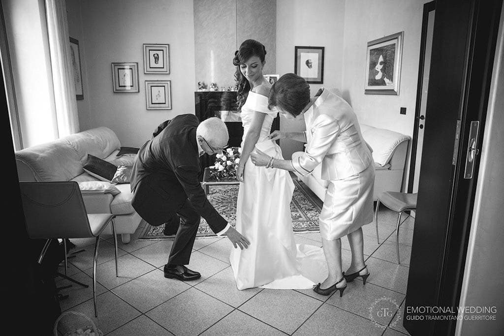 parents of the bride help her getting ready at wedding in apulia