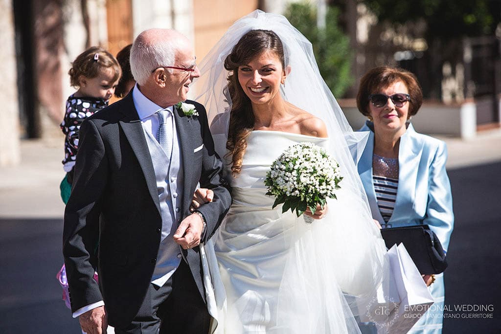 bride and her father walking towards the church at a wedding in apulia