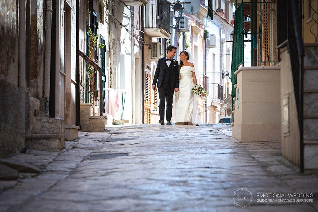 wedding couple hand in the hand looking at each other while walking in an old town in puglia