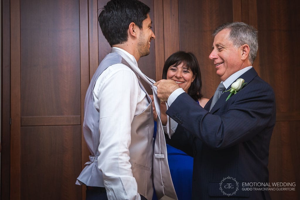 father of the groom helps the groom wearing his tie