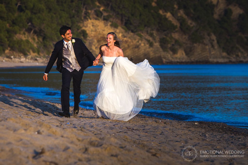 bride and groom running on a beach in Cilento