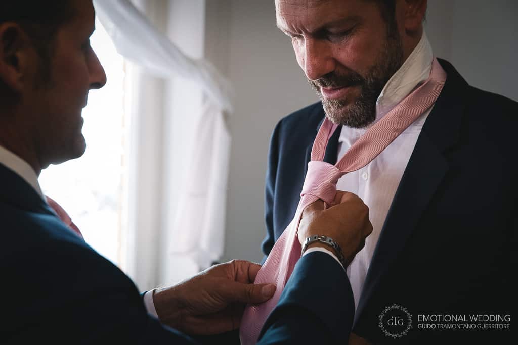 groom helping best man wearing the tie