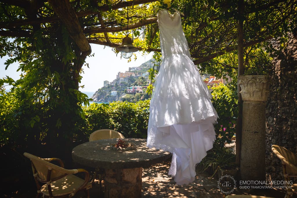 wedding dress of the bride hanged in the garden and Amalfi coast in the background