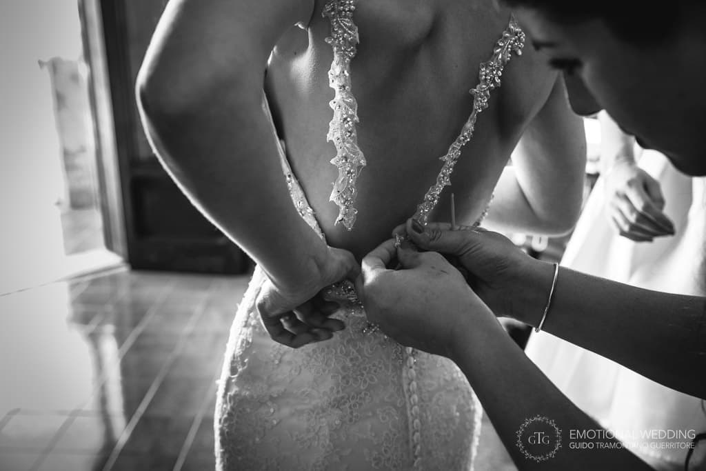 estetista allaccia l'abito alla sposa a villa scarpariello