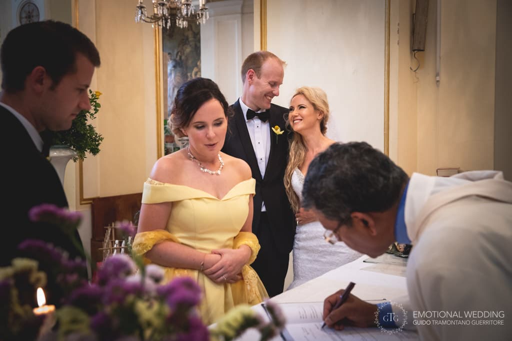 bride and groom smiling at each other while officiant signing the wedding certificate at a wedding in Amalfi coast