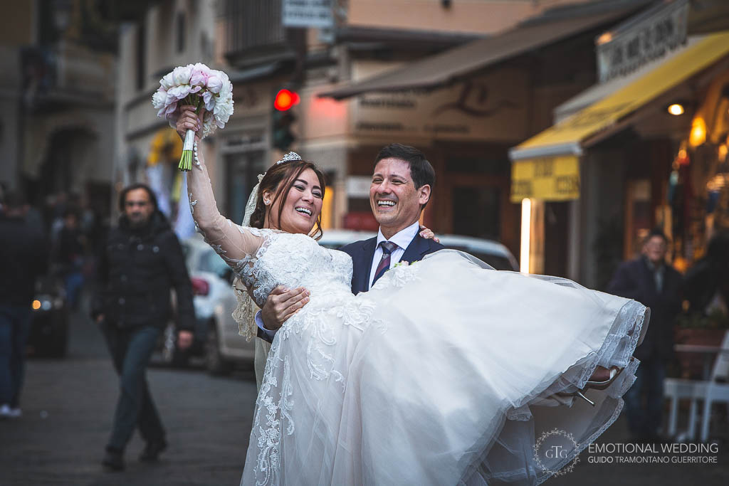 sposo prende in braccio la sposa per le strade di Amalfi al loro matrimonio