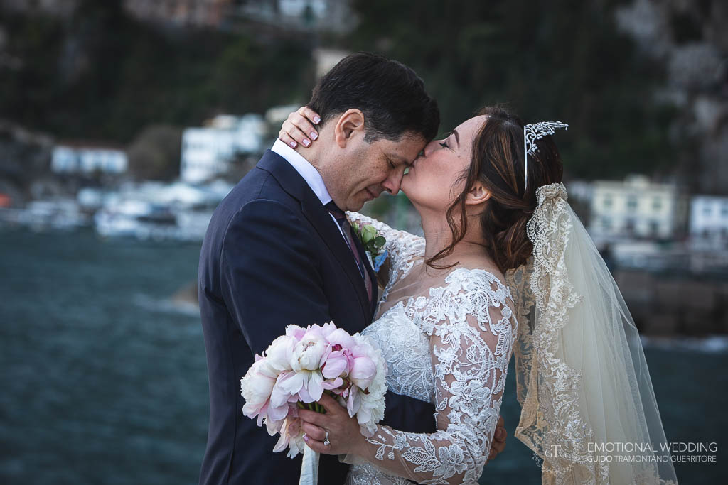 sposa bacia sposo sulla fronte al matrimonio sullo sfondo di praiano
