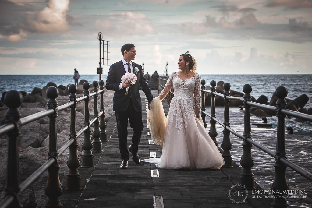 sposi passeggiano sul molo di Amalfi al loro matrimonio