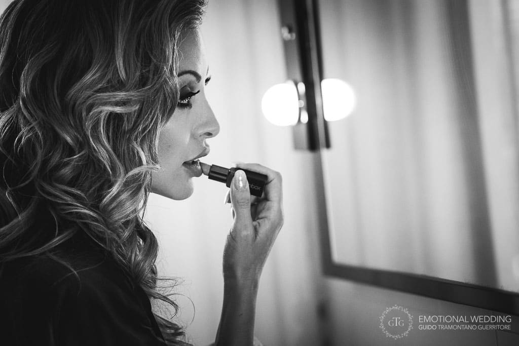 bride puts on lipstick for her wedding