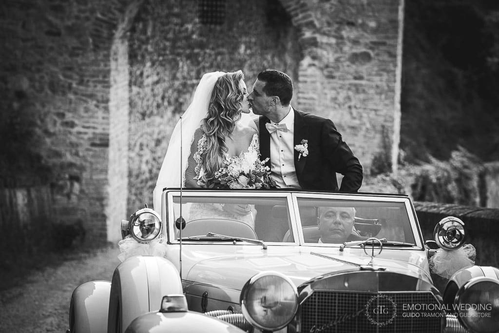 sposi si baciano in piedi in un'auto d'epoca al castello di tabiano a un matrimonio a fidenza