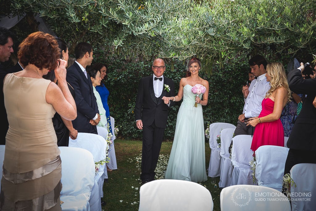 bride and her father walking to the wedding ceremony in the gardens of hotel caruso in ravello, italy