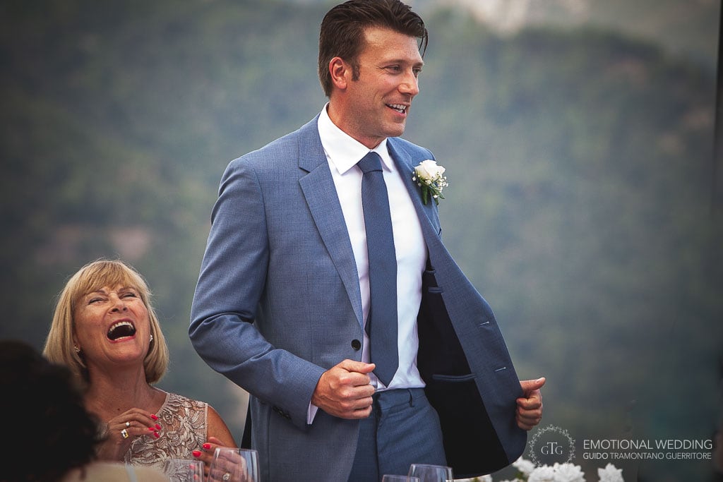 mother of the groom laughing while her son talking at guests at an italian wedding in ravello, italy