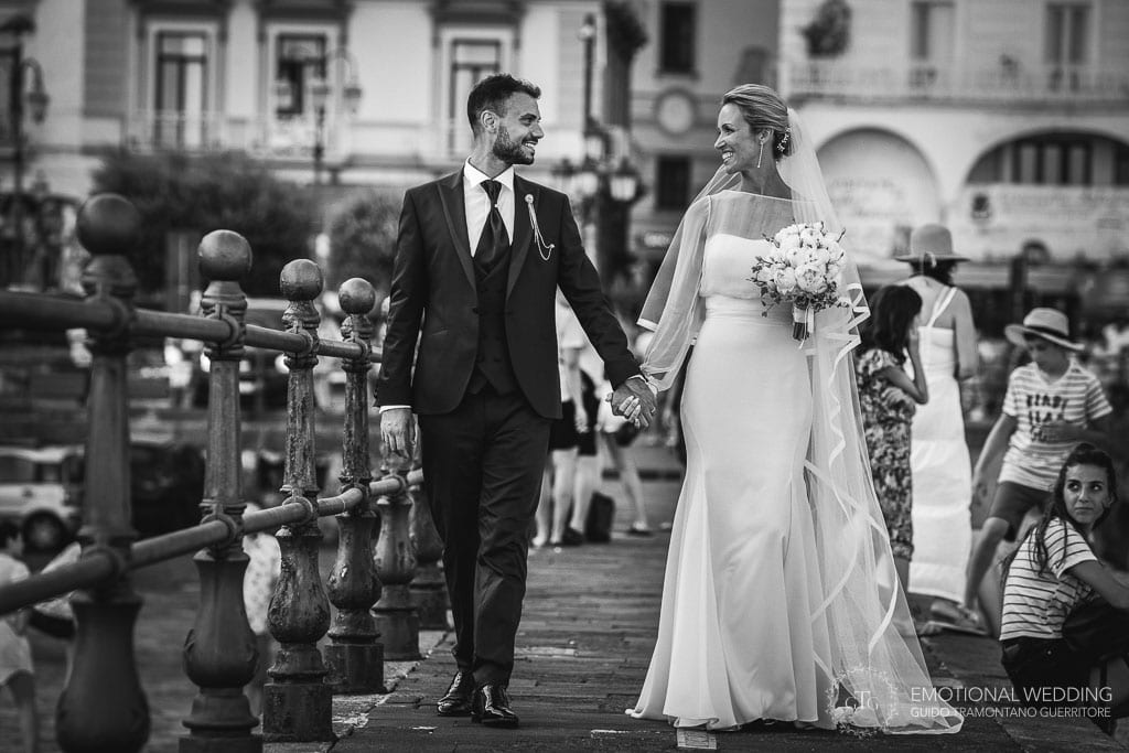 bride and groom walking and smiling on the pier in Amalfi