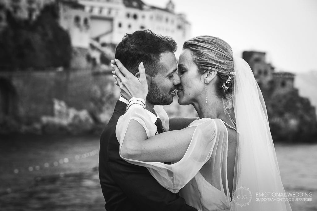 bride and groom kissing in Amalfi with Atrani in the background