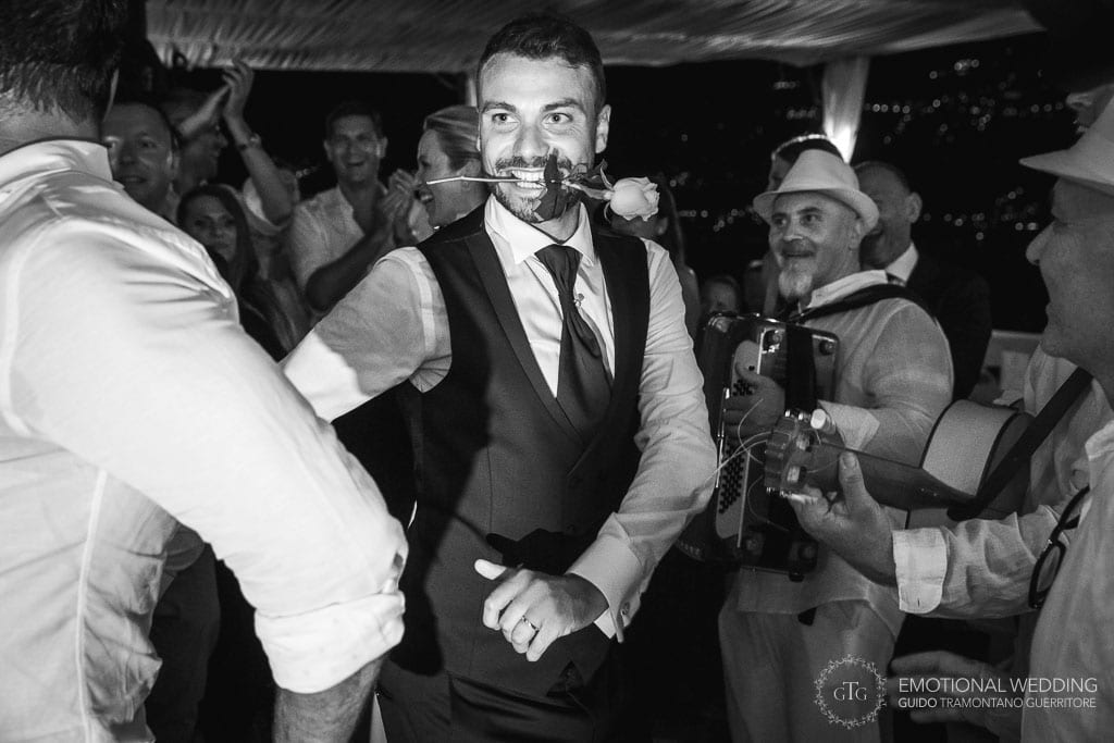 groom dancing holding a rose in his mouth