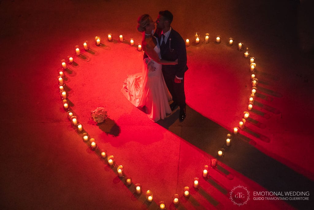 bride and groom standing inside a heart on the floor drawn with candles at Torre Normanna for their wedding in Maiori