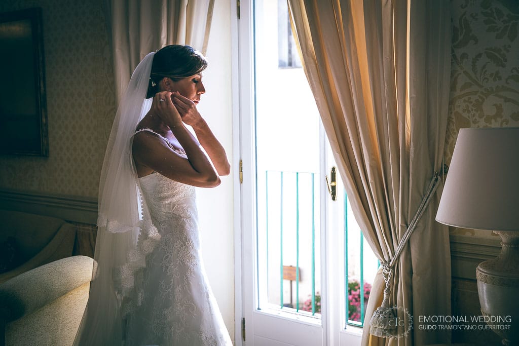 sposa indossa orecchini davanti alla finestra al belmond hotel caruso