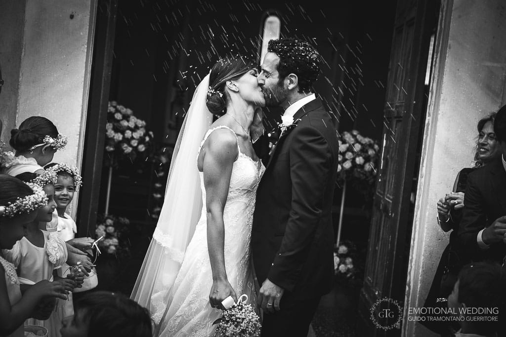 bride and groom kissing under a shower of rice