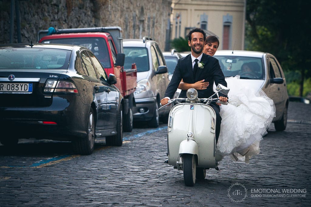 wedding couple riding a vintage scooter in the streets of ravello