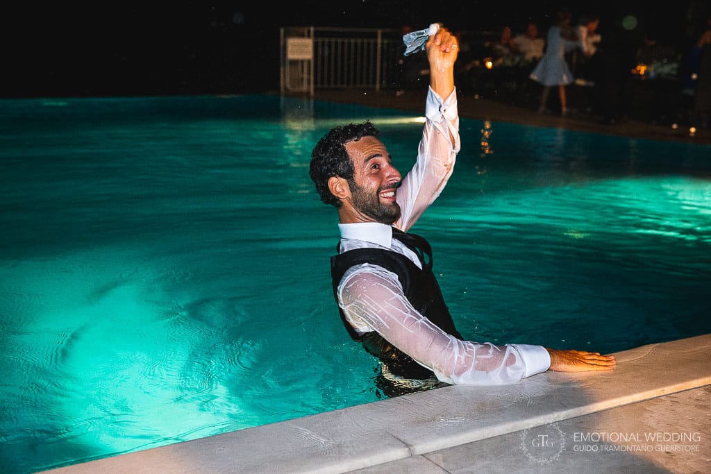 groom in the infinity pool at hotel Caruso shaking the bride's garter in his hand