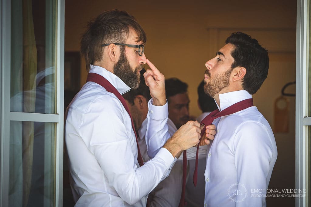 groom joking with best man while gets help wearing the tie at a wedding in sorrento