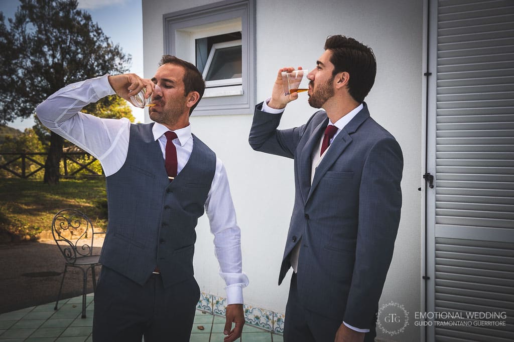 groom and best man drinking whisky after getting ready for the wedding ceremony in sorrento