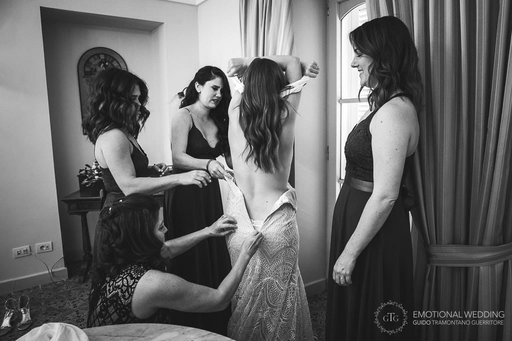 bridesmaids help the bride wearing her wedding dress in sorrento