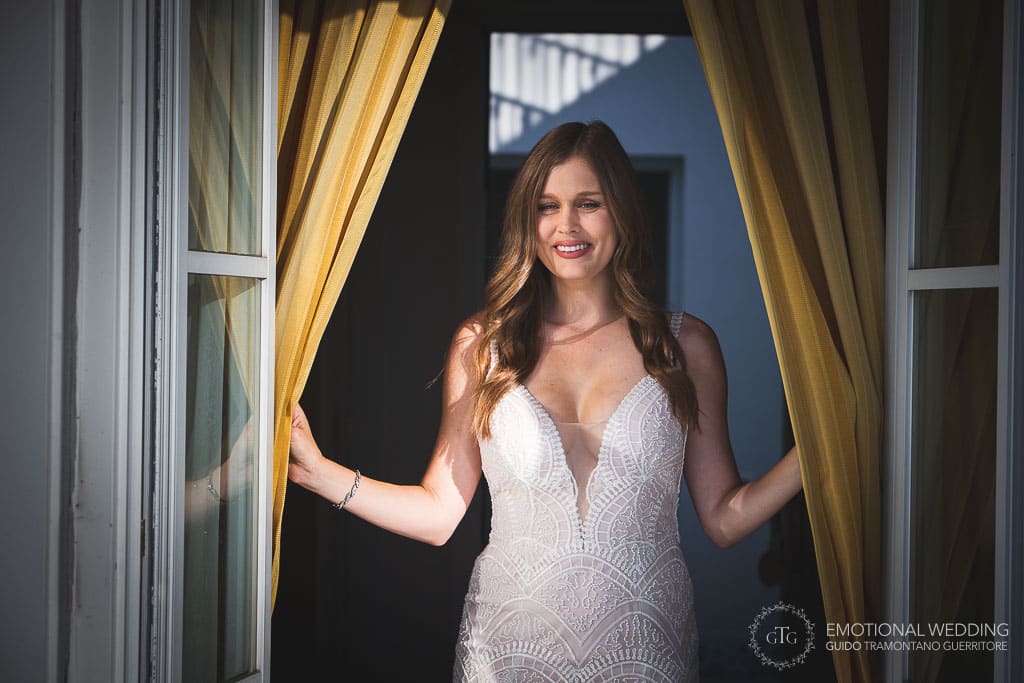 sposa si affaccia alla finestra della camera a villa olimpia a un matrimonio a sorrento