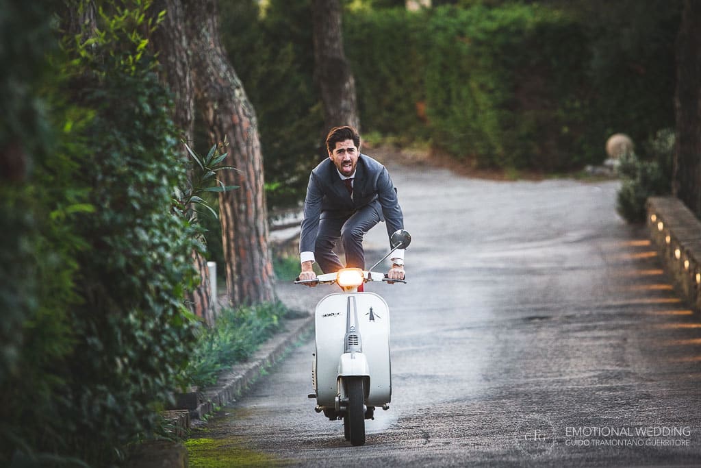 groom riding a motorbike standing on his feet on the seat at a wedding in Sorrento