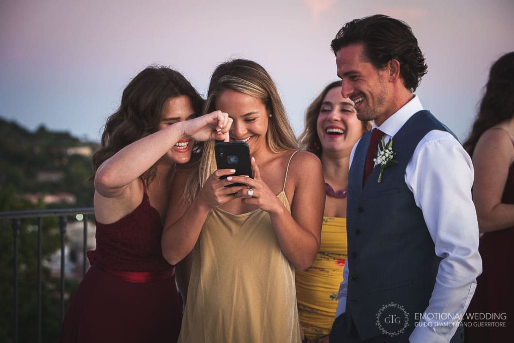 guests smile looking at photos on smartphone at a wedding in Sorrento