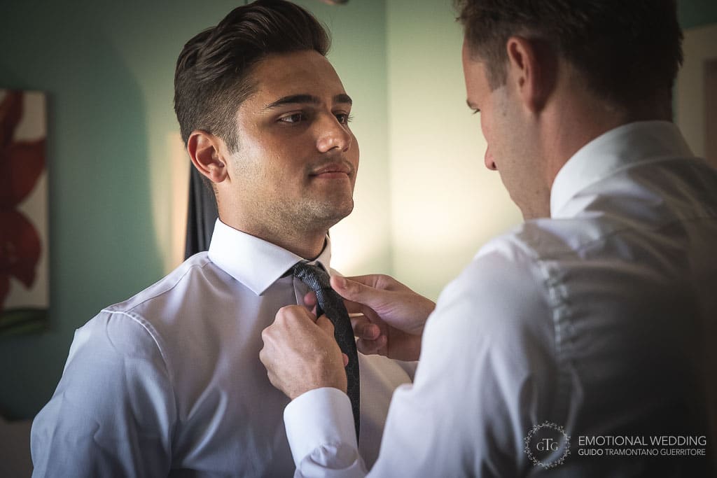 sposo aiuta testimone ad indossare la cravatta ad un matrimonio in toscana