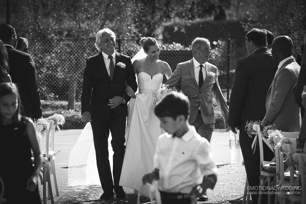 bride walking down the aisle on a tennis court at Locanda Rossa in tuscany