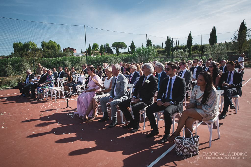 guests at a wedding ceremony in a tennis court in tuscany