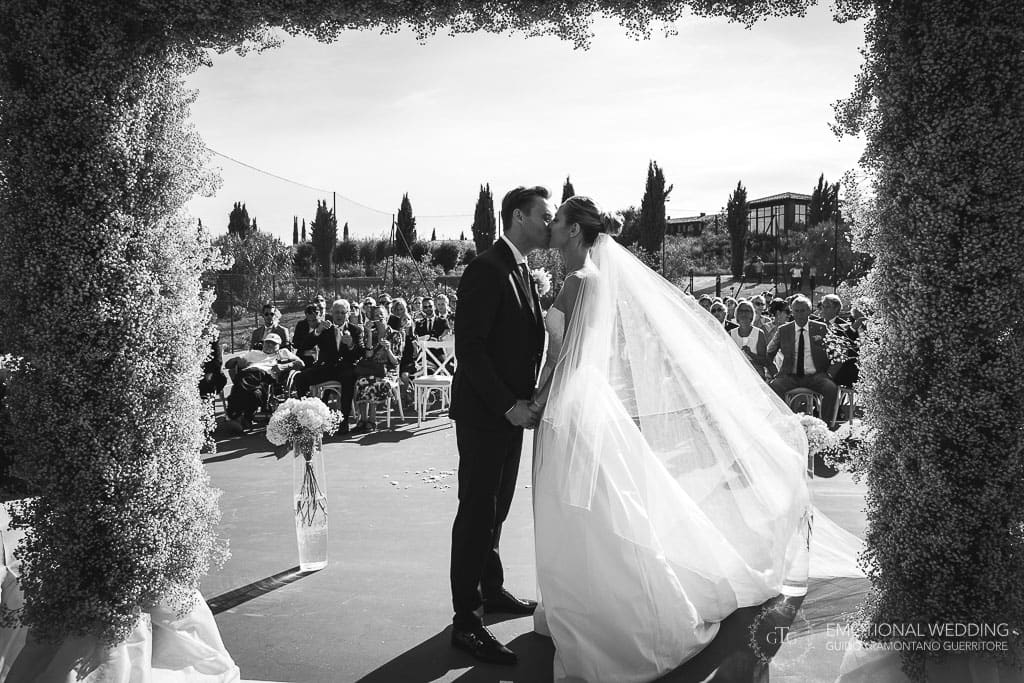 bride and groom kissing during wedding ceremony in tuscany