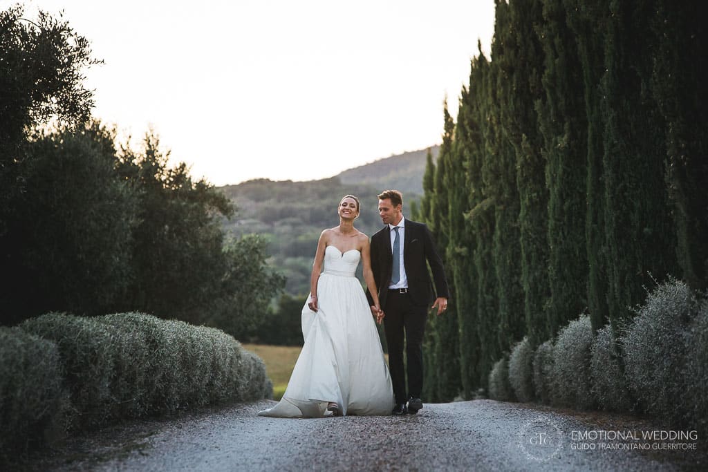 wedding couple walking on a path surrounded by cypress in tuscany