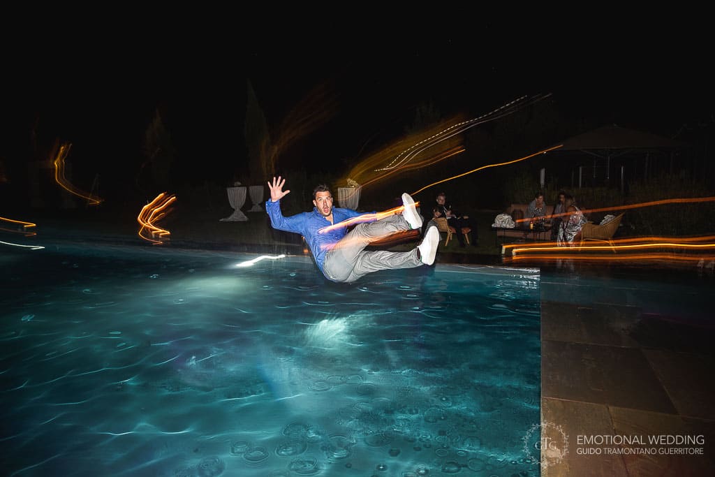 guest jumping into the pool during a wedding party in tuscany