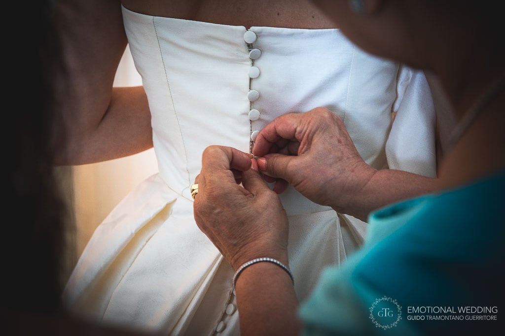 mother of the bride buttons up the bride's dress for her wedding in praiano