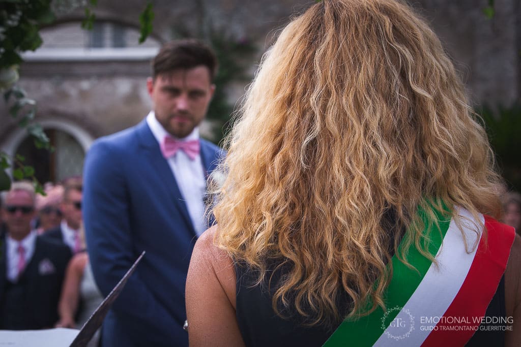 Italian officiant and groom in the background at principessa di Piemonte town hall during a wedding ceremony in ravello