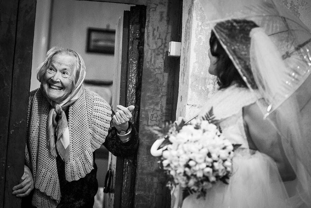 an elderly lady meets the newlyweds at the doorstep of her house on the Amalfi coast