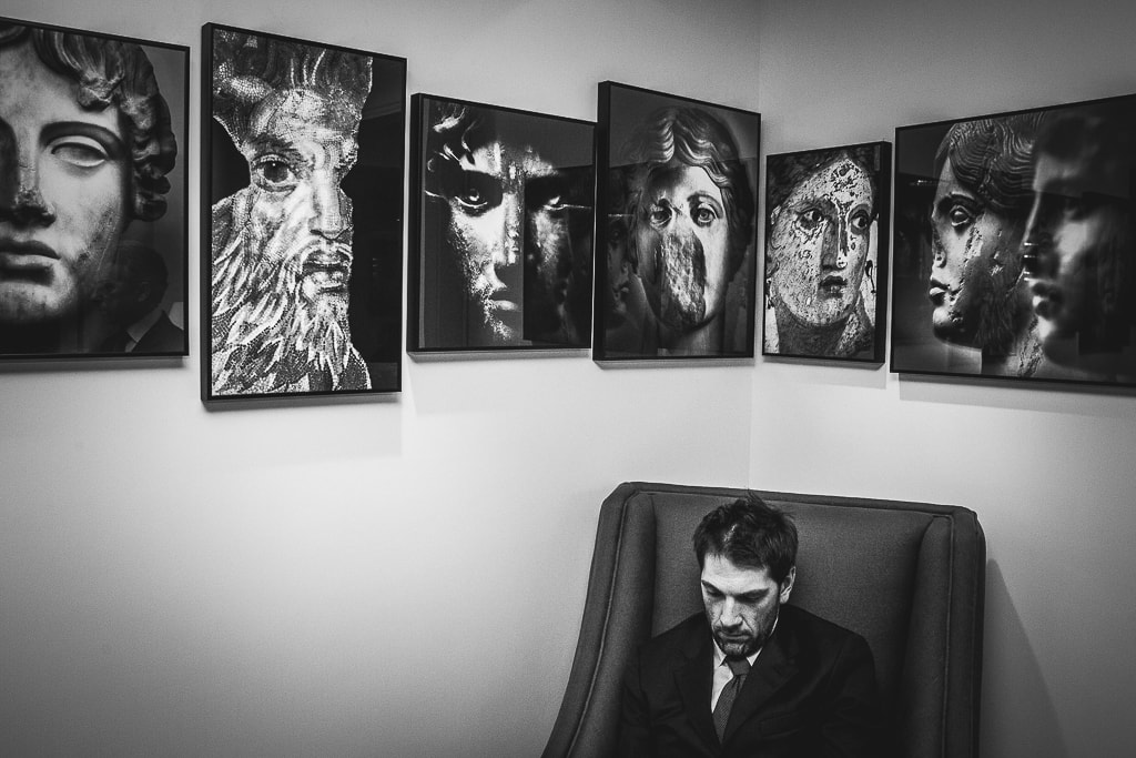 a man sitting in an armchair that looks like the portraits hanged on the wall behind him