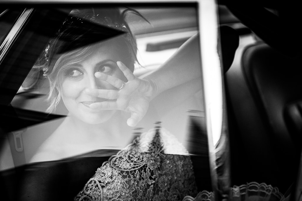 bride says hello with her hand as her car leaves
