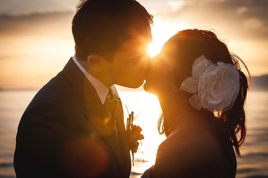 wedding couple kiss in a warm light against the sun