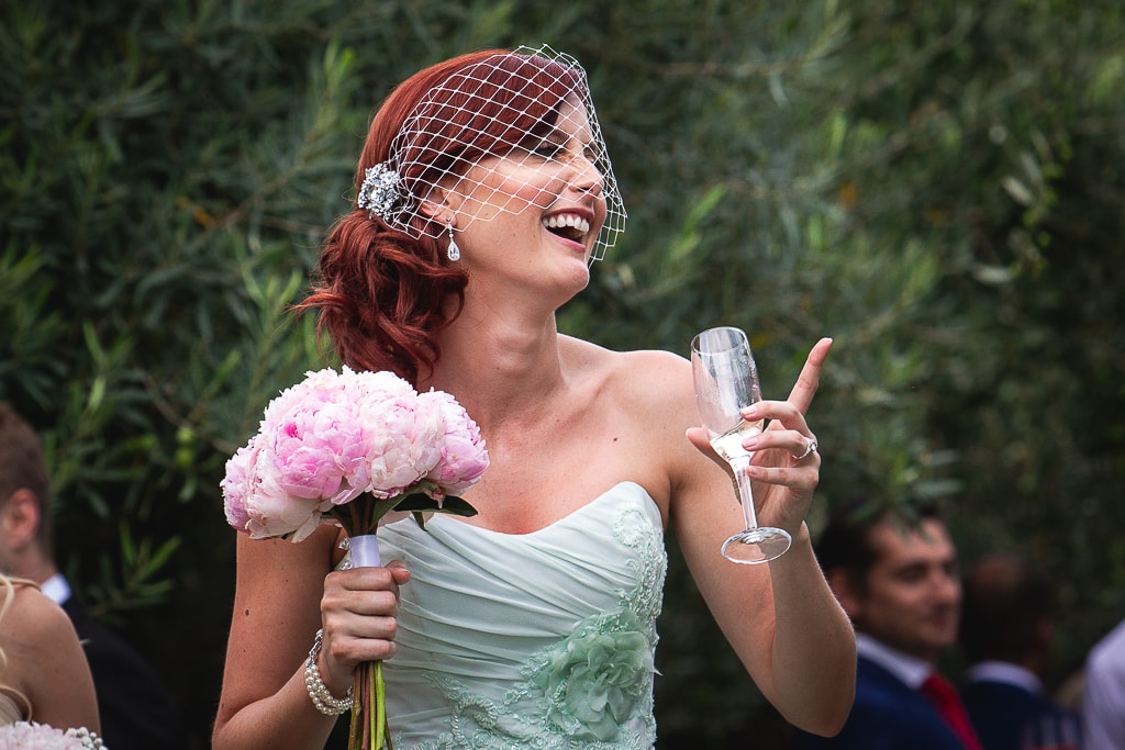 a bride holding a glass and laughing