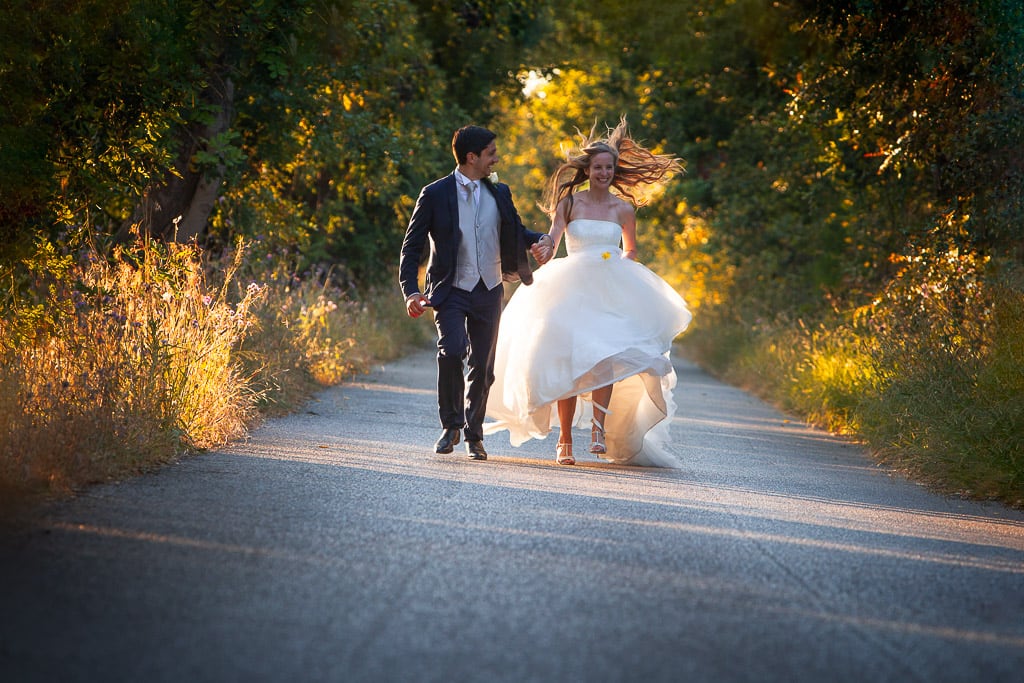wedding couple running on a countryside road