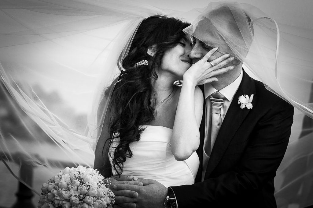 wedding couple kiss under a flying veil